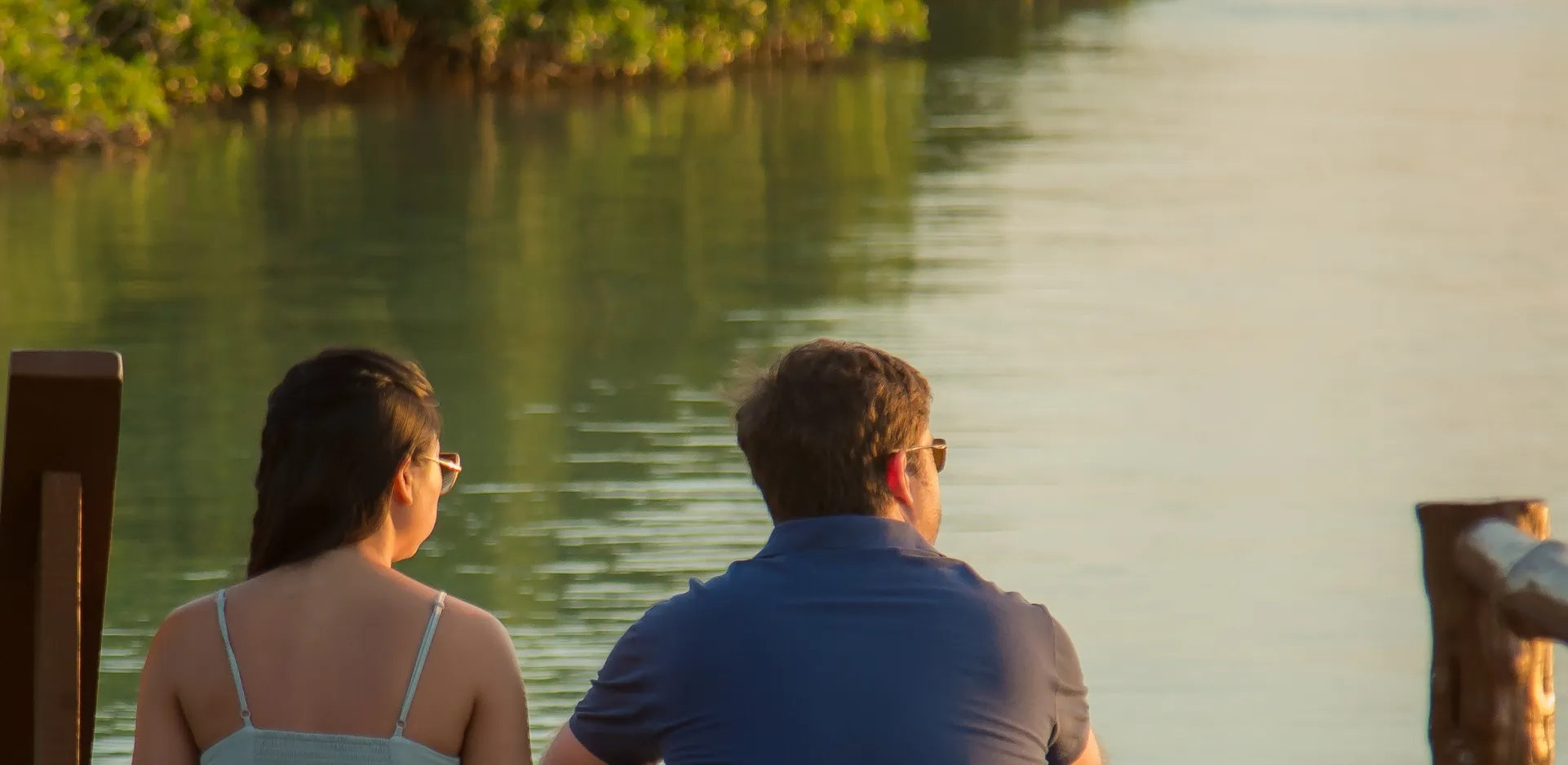 a man and a woman sitting on a dock looking at the water, an impressionist painting by Avigdor Arikha, featured on unsplash, american romanticism, anamorphic lens flare, shallow depth of field, depth of field